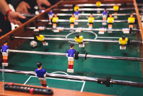 Fotografija Group of friends playing kicker in a sports bar room, colleagues teammates play