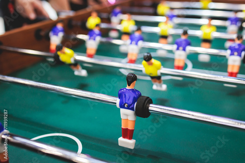 Group of friends playing kicker in a sports bar room, colleagues teammates play table football, table soccer game in the office, having fun, tabletop football match competition at work © tsuguliev