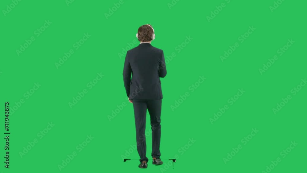 Back shot of male model in suit isolated on chroma key green screen background. Young businessman office worker in suit walking in headphones. Back shot of male model in suit isolated on chroma key green screen background. Young businessman office worker in suit walking in headphones.