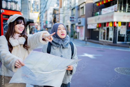 woman girl tourist Two Asian friends but different religions, one of whom is a Muslim girl. Looking at the tour map View information on traveling in Japan. with fun She is traveling in the city area. © maya1313
