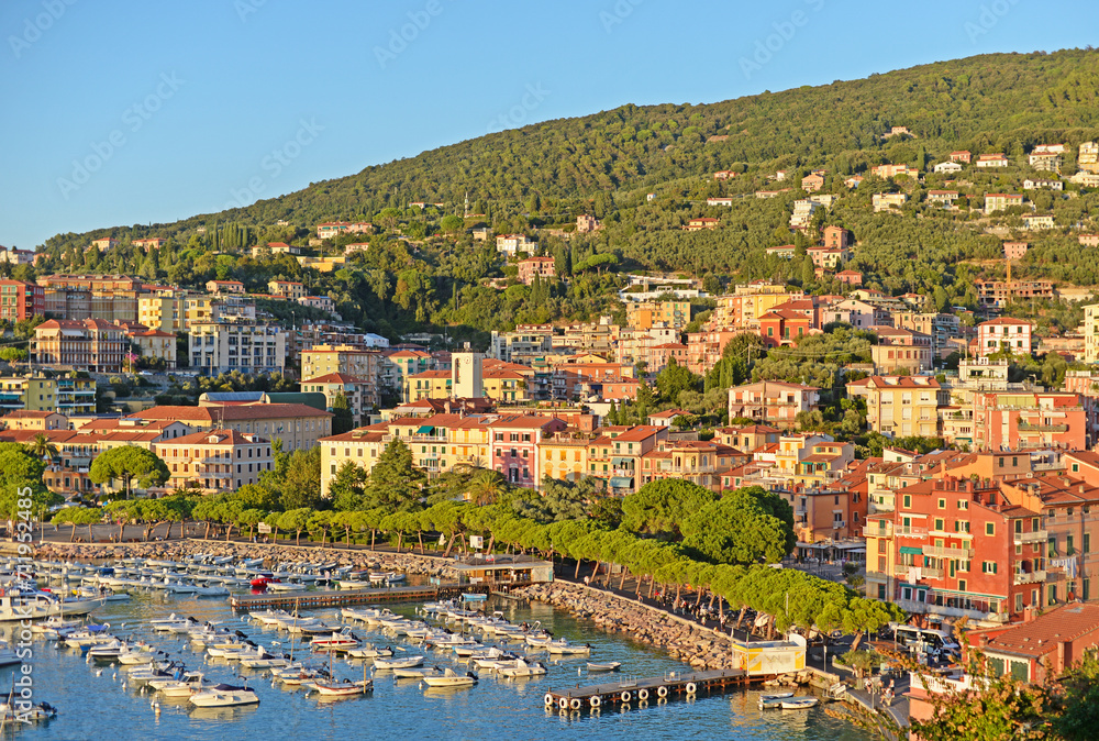 View on Lerici marina, pier, promenade, hill and the colouorful city centre in the Gulf of La Spezia in Liguria, Italy on a sunny summer evening with blue sky