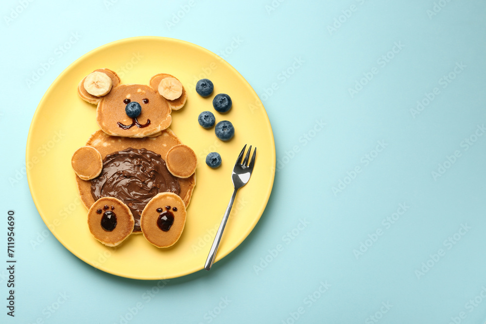 Obraz na płótnie Creative serving for kids. Plate with cute bear made of pancakes, blueberries, bananas and chocolate paste on light blue table, top view. Space for text w salonie