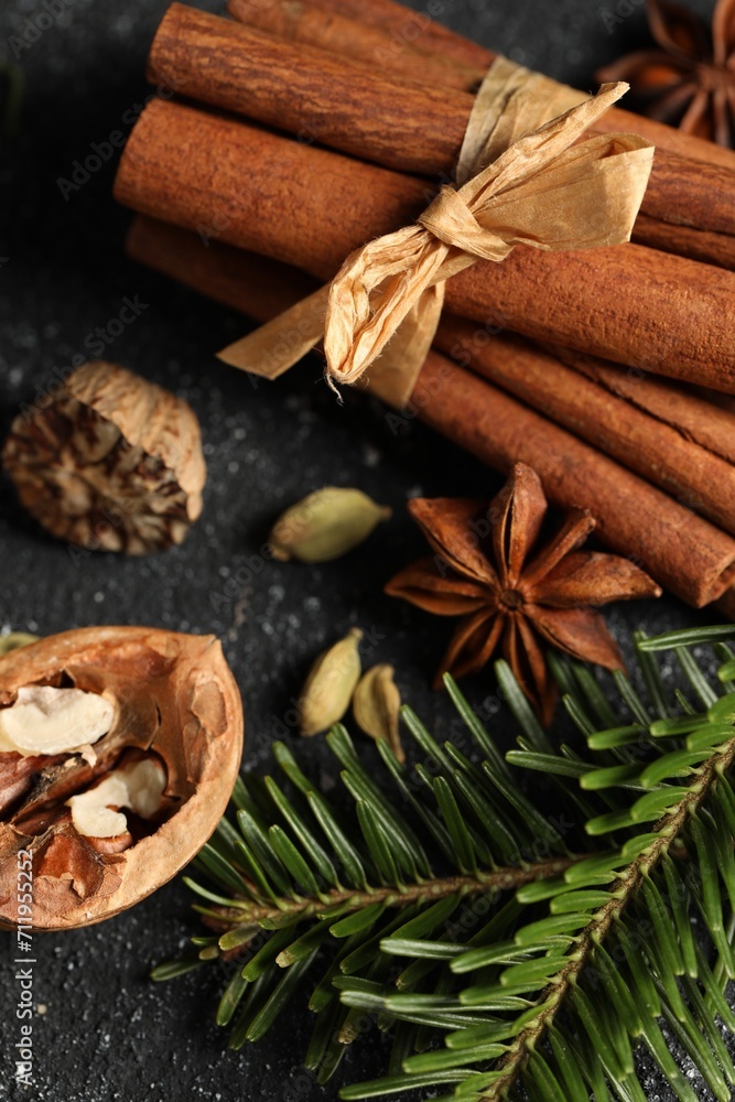 Different aromatic spices and fir branches on grey textured table, closeup