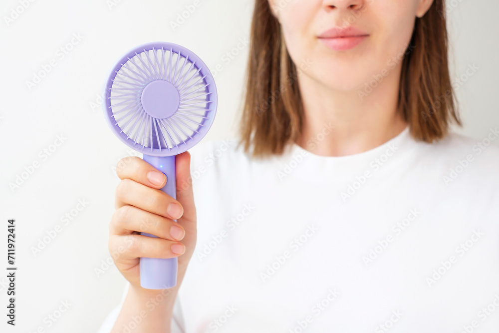 Young woman holding mini fan on white background close-up. Young woman holding mini fan on white background close-up.