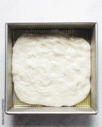 Focaccia dough rising in a square baking pan, process of making focaccia, bread dough rising in a baking pan