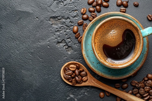 Overhead shot of a cup of coffee on a dark textured surface with coffee beans.