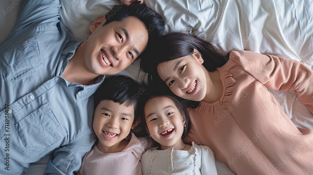 Happy Asian family lying on bed in bedroom with happy and smile, top view Happy Asian family lying on bed in bedroom with happy and smile, top view
