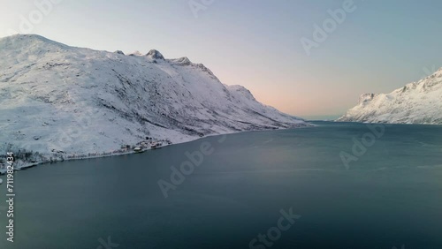 Aerial establishing shot of a frozen lake between mountains in ersfjordvegen