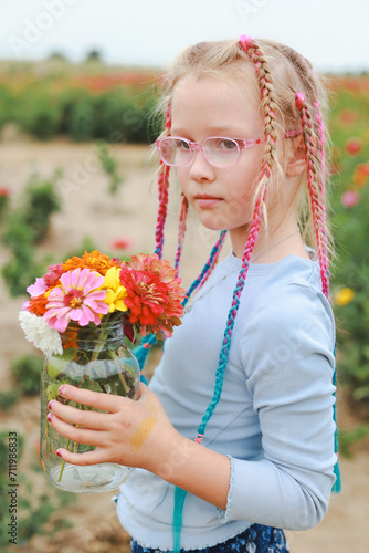 girl with colorful pigtails holding a vase with fresh cut colorful flowers