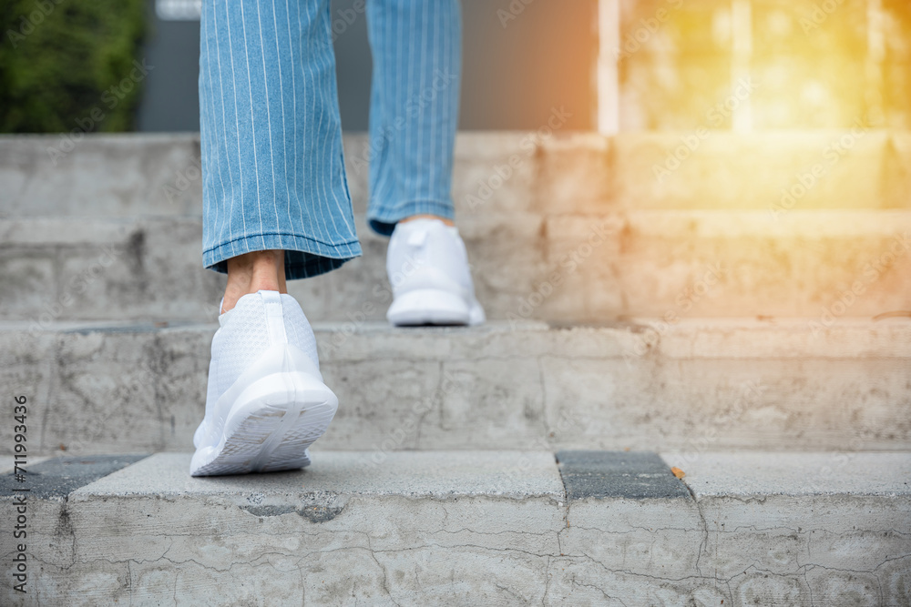 With sneakers on, a woman takes on the city stairway, showcasing her determination and progress. Each step is a reflection of her unwavering journey towards success and personal growth. step up
