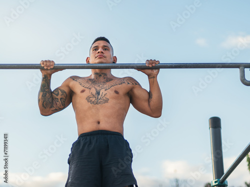 male athlete doing pull ups on a bar outdoors. calisthenics