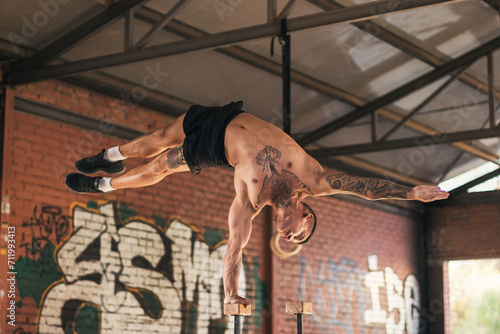 male athlete doing one hand handstand
