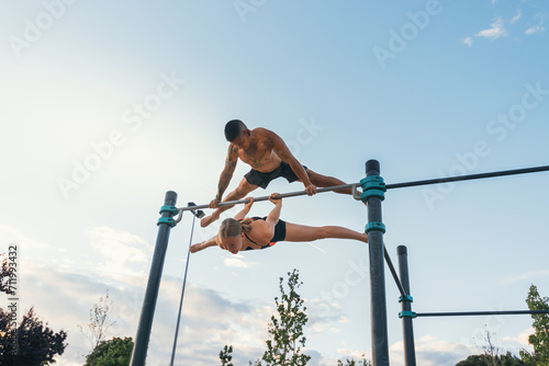 couple training together in a calisthenics park. doing back lever and straddle planche.