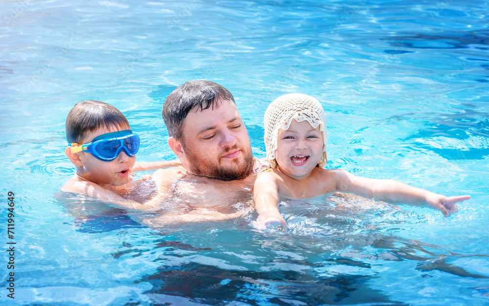 Fototapeta premium Portrait of a father with children in the pool