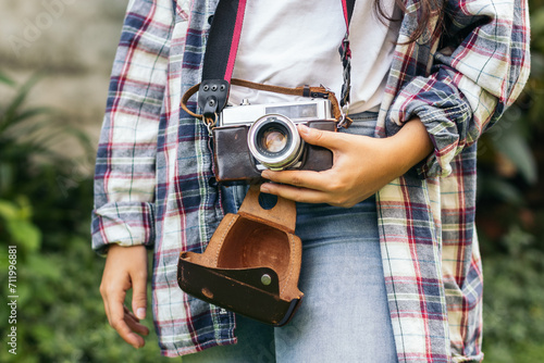 Unrecognizable woman taking photos with analog camera in the field at sunset photo