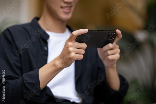 A man using his smartphone, playing a mobile game or watching a video while sitting in a coffee shop