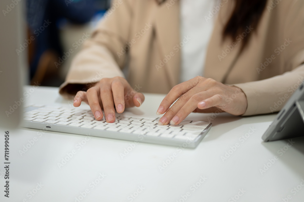 Fototapeta premium Close-up image of a businesswoman working at her desk in the office, typing on keyboard computer.
