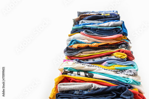 A very tall stack of folded colored clothes for charity, washing, ironing and sorting.