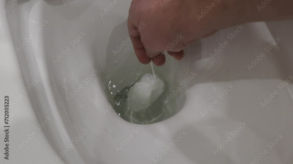 man hand taking out used feminine hygiene tampon thrown into the toilet