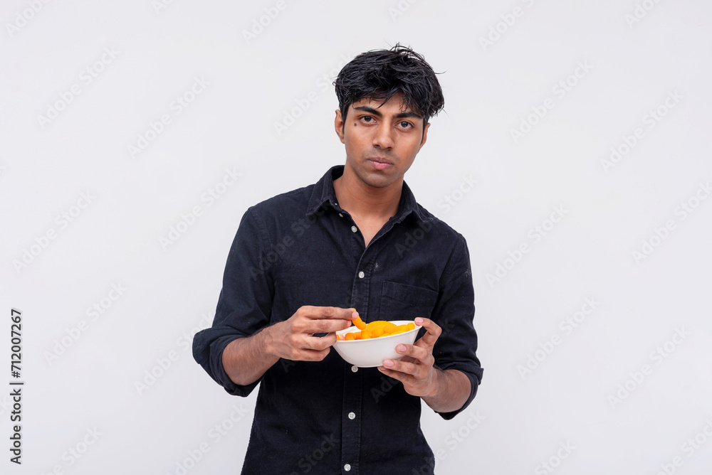 Young man with uncertain expression holding snacks Young man with uncertain expression holding snacks