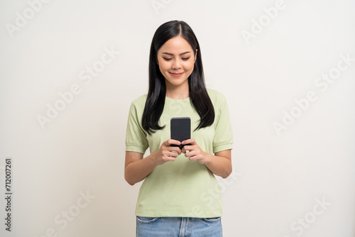 Pretty young asian woman using cellphone standing on isolated white background. Happy Excited Beautiful young asian shopping online payment with mobile phone. Playing game on smartphone