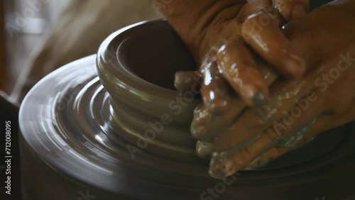 Close up of hands shaping pot on ceramic lathe pottery rotating. Handheld photo