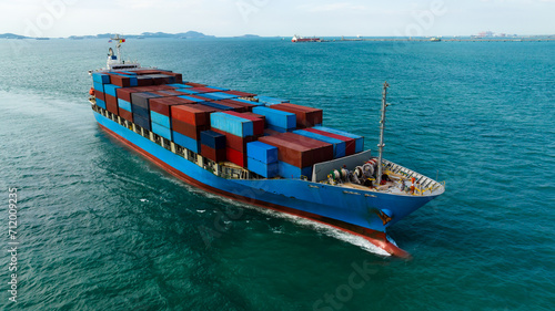 logistic cargo container ship sailing in sea to import export goods and distributing products to dealer and consumers across worldwide, aerial front view