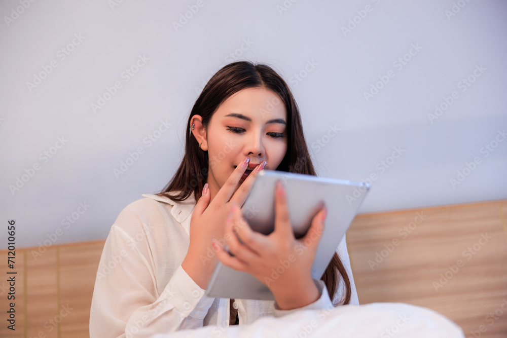 Young asian woman sitting on bed in bedroom using tablet shopping online. Young asian woman sitting on bed in bedroom using tablet shopping online.