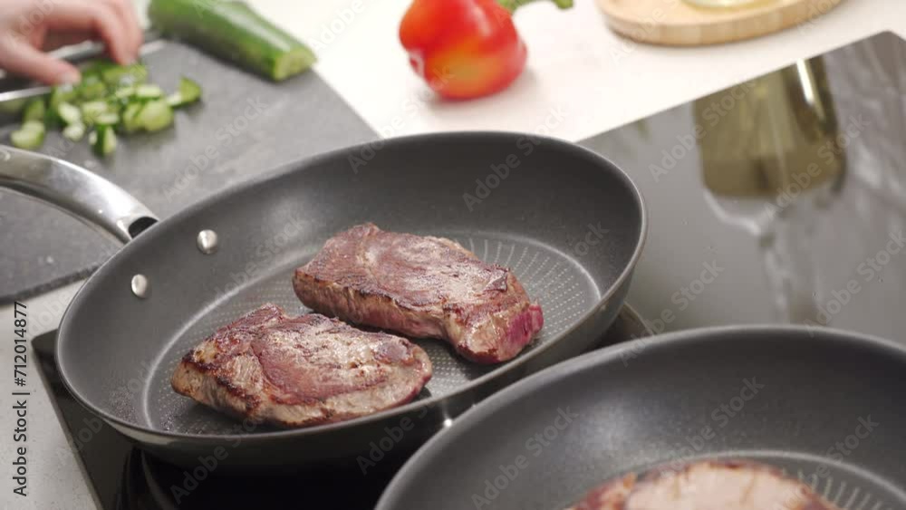 Cooking fried steak, frying beef steaks in a frying pan on the stove in the kitchen Cooking fried steak, frying beef steaks in a frying pan on the stove in the kitchen