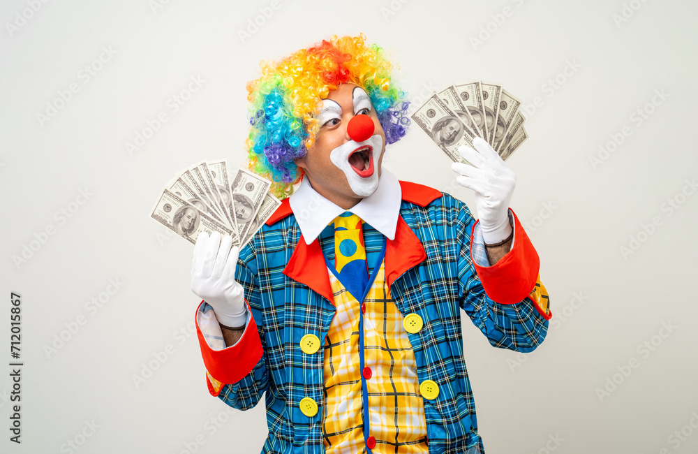 Mr Clown. Portrait of Funny face Clown man in colorful uniform standing holding a lot of money for gambling. Happy expression male bozo in various pose on isolated background. Mr Clown. Portrait of Funny face Clown man in colorful uniform standing holding a lot of money for gambling. Happy expression male bozo in various pose on isolated background.