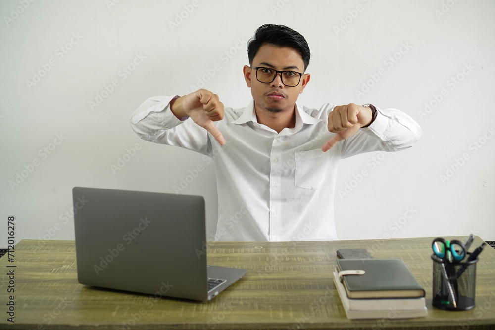 young asian businessman in a workplace showing thumb down wear white shirt with glasses isolated young asian businessman in a workplace showing thumb down wear white shirt with glasses isolated