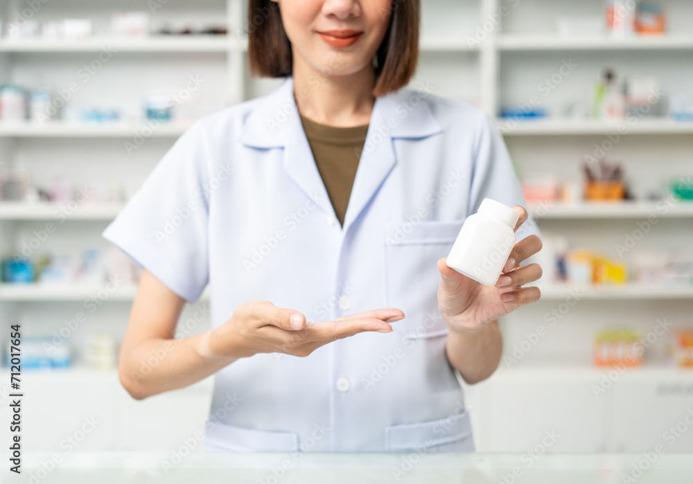 Close up woman hands holding medicine bottle near drug shelves. Pharmacist checks inventory of medicine in pharmacy drugstore. Professional Female Pharmacist wearing uniform
