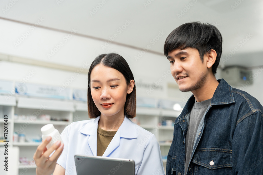 Pharmacist recommends medicines to customers.Taking the questions of medication. Asian female pharmacist giving prescription medications to customers at drugstore shelves. Pharmacist recommends medicines to customers.Taking the questions of medication. Asian female pharmacist giving prescription medications to customers at drugstore shelves.