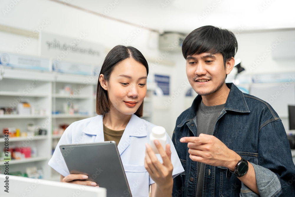 Obraz premium Pharmacist recommends medicines to customers.Taking the questions of medication. Asian female pharmacist giving prescription medications to customers at drugstore shelves.