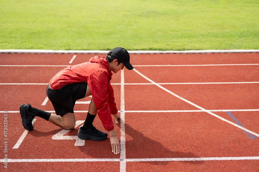 Young handsome indian man doing start pose before running exercise on track in sport stadium. Challenge race of athletes running in the starting point. Young asian man in sport athlete uniform Young handsome indian man doing start pose before running exercise on track in sport stadium. Challenge race of athletes running in the starting point. Young asian man in sport athlete uniform
