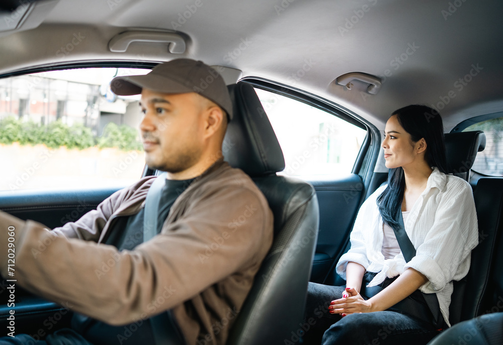 Young asian woman traveling in the downtown city with taxi driver service. Female passenger sitting in backseat calling taxi driver by application.