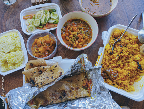 Overhead view of colorful array of Indian food in takeout containers