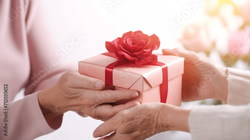 Closeup on hands. Elderly woman giving a gift box to elderly or old woman for Birthday © Teerasak