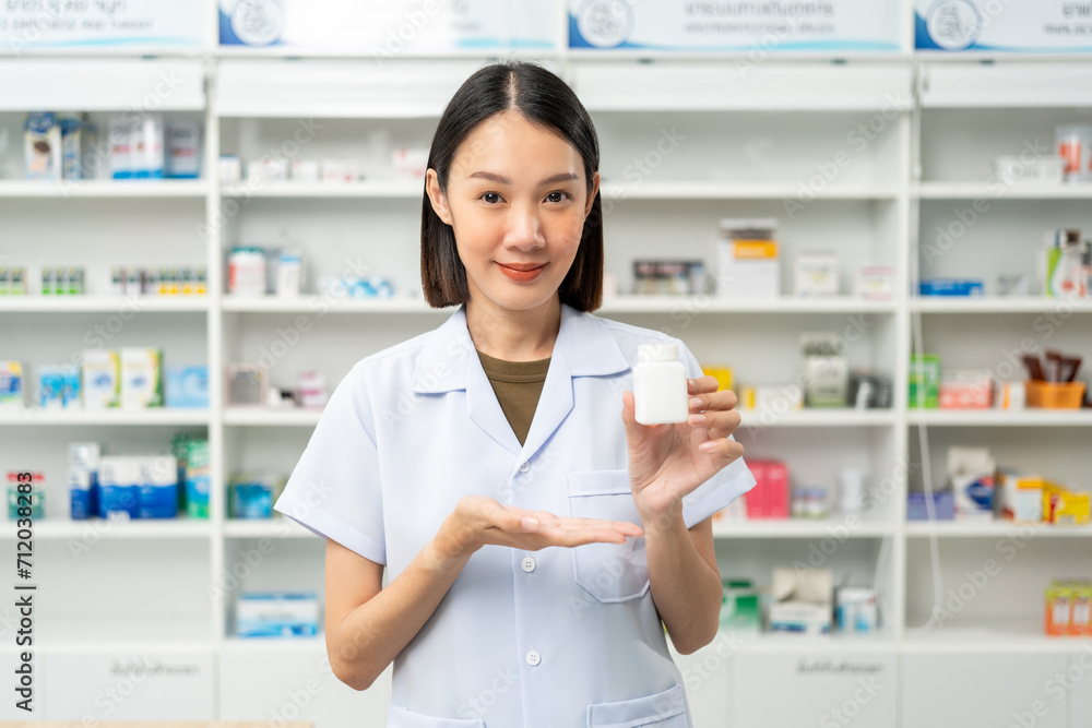 Professional Pharmacist woman in uniform holding medicine bottle near drug shelves counter. Pharmacist checks inventory of medicine in pharmacy drugstore.