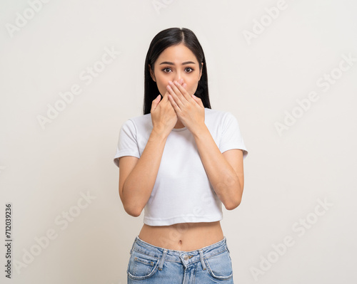 Oops. Shocked face asian woman while hands close mouth keep quiet. Can't speak no vote. Young latin female worried expression keep the secret. Attractive Asian woman standing on white background