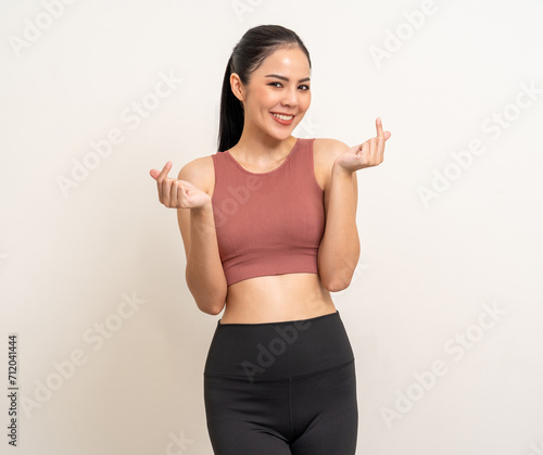 Young beautiful smiling asian woman with sportswear showing mini heart on isolated white background. Portrait happy healthy slim fit and firm latin attractive sporty woman heart sign pose © Chanakon