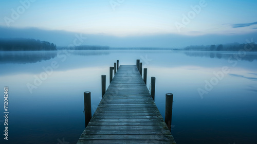 Serenely Misty Lake at Dawn with a Wooden Jetty Leading into Calm Waters, Evoking Peacefulness and Reflection