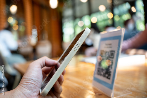 Woman use smartphone to scan QR code for order menu in cafe restaurant with a digital delivery. Choose menu and order accumulate discount. E wallet, technology, pay online, credit card, bank app. photo