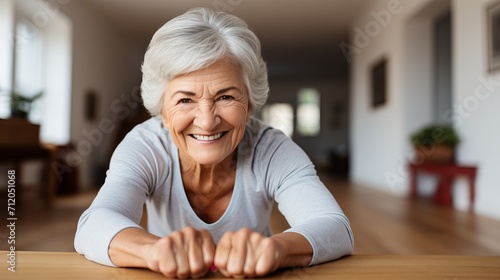 Vibrant senior woman smiling while excellently performing cobra pose exercise at home photo