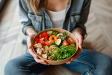 Girl holds a plate with healthy food sitting on the floor. Healthy eating concept. Take away food to home.
