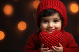 Pakhistan toddler boy child holds knitted red heart toy in hands on studio background. Health heart, care, giving sharing love, need help, charity Valentine's day and kids healthcare love concept