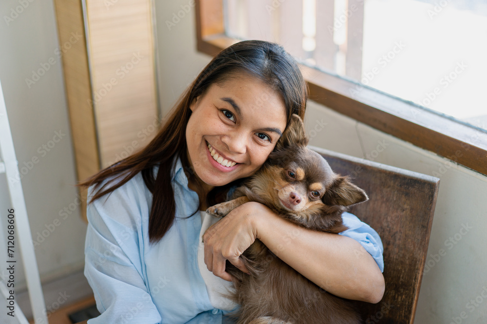 Joyful fit woman sitting having fun with cute dog on the armchair at living room one autumn day , friendship and love for pets. Joyful fit woman sitting having fun with cute dog on the armchair at living room one autumn day , friendship and love for pets.