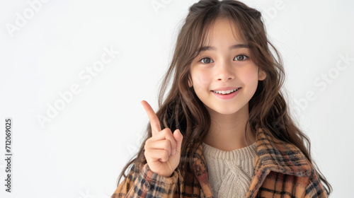 Beautiful Asian girl, pointing finger up at copy space isolated on background.