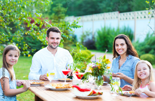 Happy family of four people enjoying meal together outdoors