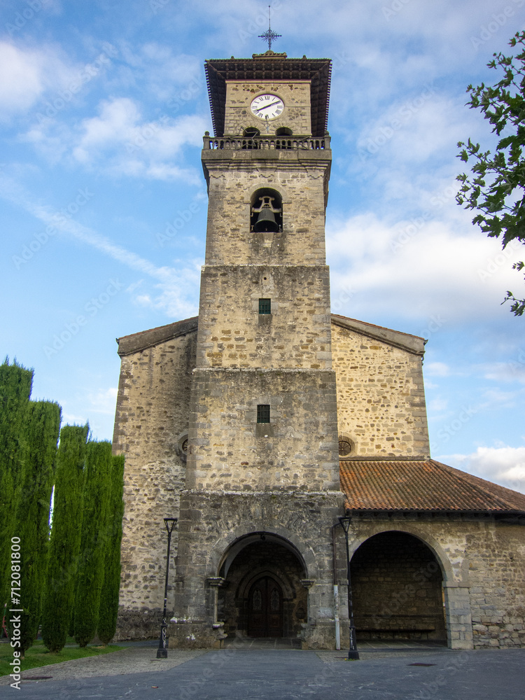 Main façade of the medieval gothic church of Santa María in Amurrio with its large stone tower and clock in the Basque Country.